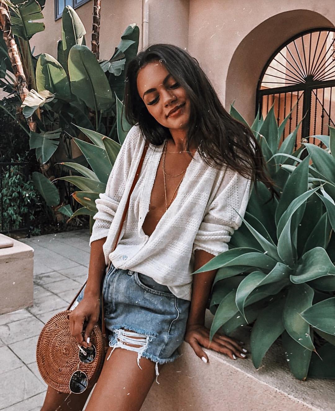 Summer vacay look: peasant top in white, ripped denim shorts and straw sack 2021