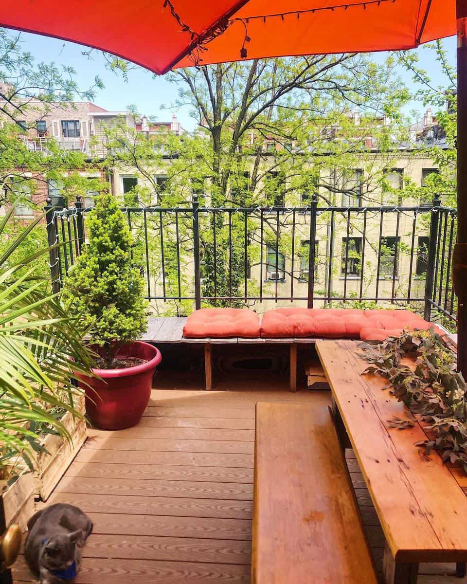 small apartment wooden deck black railing plants 