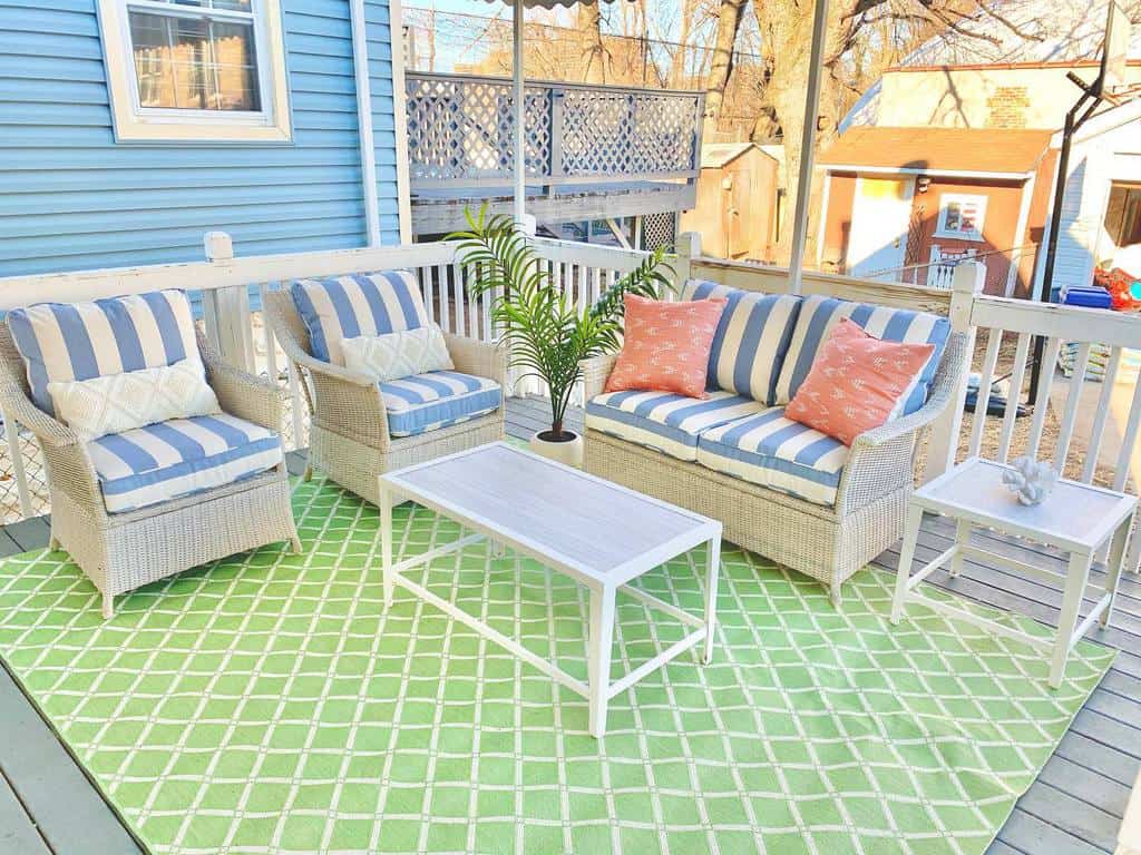 Pastel patio rug with green pattern, blue and white cushions 