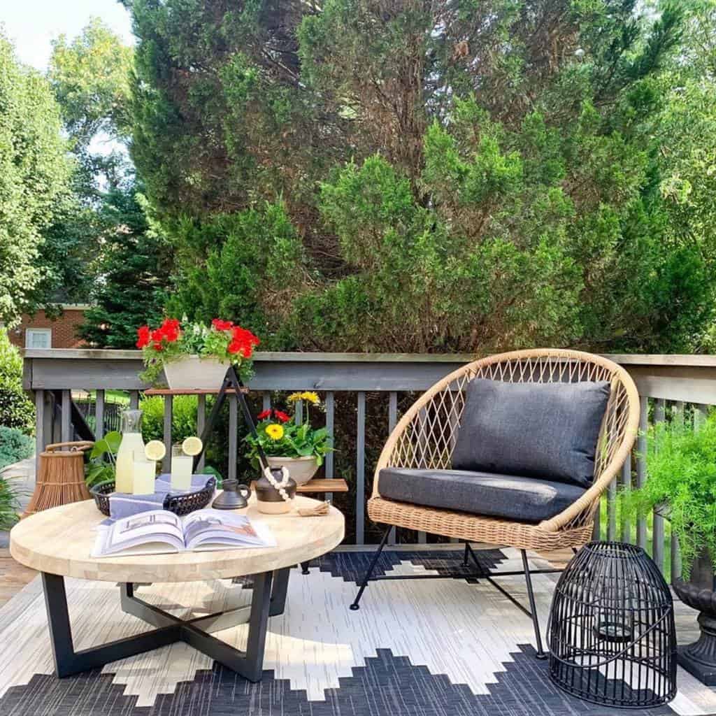 Outside deck floor carpet, small table, wicker chair 