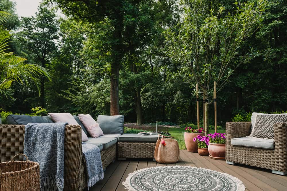 Outdoor deck, wicker furniture, large green backyard 