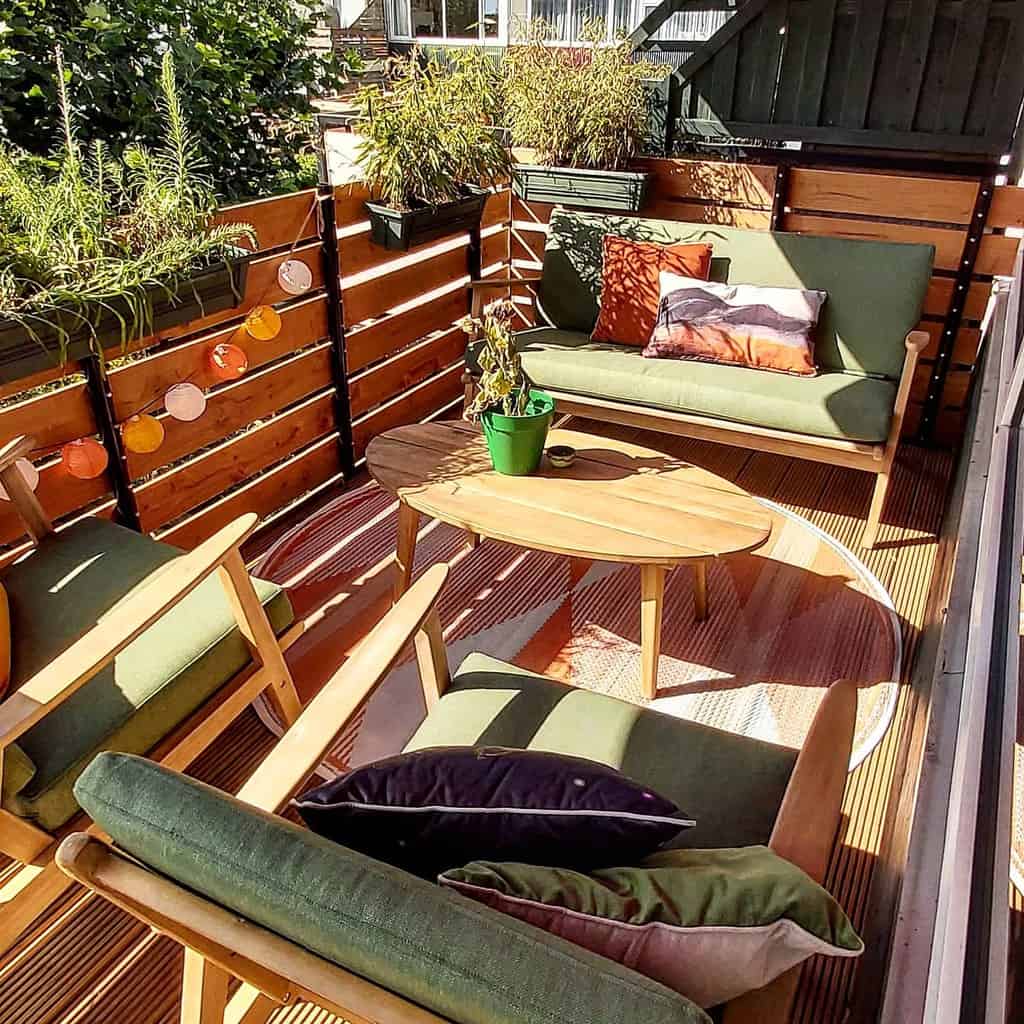 Balcony terrace with wooden privacy fence and green cushion furniture 