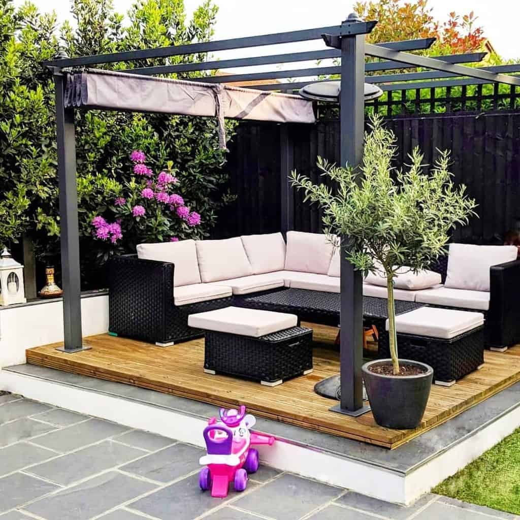 Wooden terrace with metal pergola and black wicker furniture 