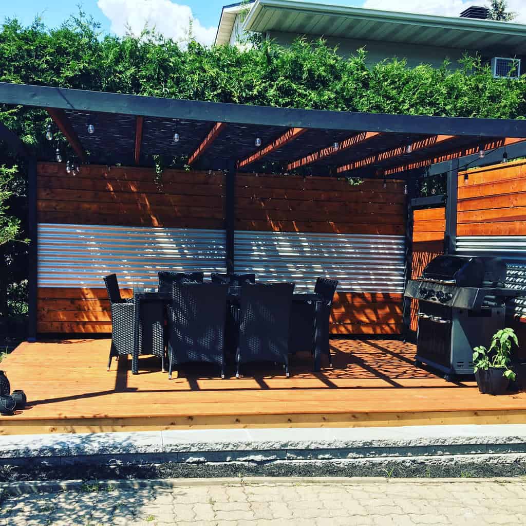 Black pergola with wooden deck and wicker furniture 