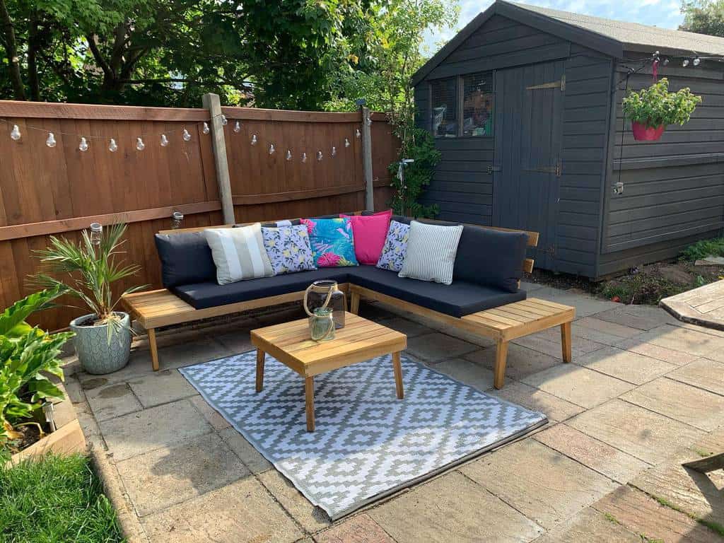 small garden terrace with fairy lights and wooden seating 