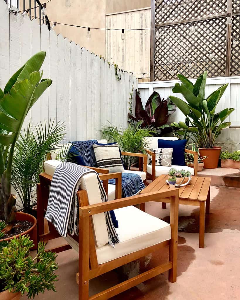 Garden terrace with wooden table and chairs and white cushions 